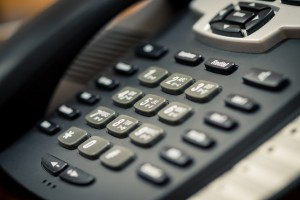 A close up of a Black office IP Phone on a desk
